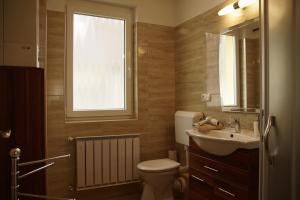 a bathroom with a toilet and a sink and a window at Bodó Park Apartment in Hévíz +22 photos