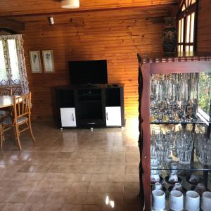 ein Wohnzimmer mit einem TV und einem Tisch mit Gläsern in der Unterkunft Chalé Dei Fiori, 3QTS, Ambiente Ideal para a família in Venda Nova do Imigrante