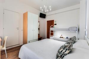 a white bedroom with two beds and a chandelier at Hotel Geminus B&B in Cesenatico