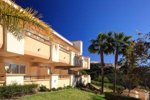 una casa con palmeras delante en Hotel - Apartamentos Greenlife Golf, en Marbella