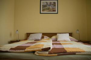 a bedroom with a bed with a blanket and two lamps at Bodó Park Apartment in Hévíz