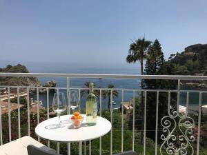 una mesa con una botella de vino y copas en el balcón en B&B A Due Passi Dal Mare, en Taormina