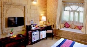 een slaapkamer met een bed en een televisie en een spiegel bij Golden Haveli in Jaisalmer