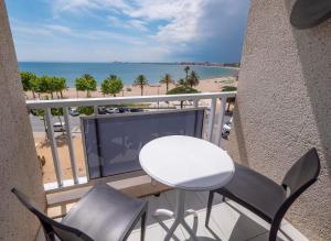 een balkon met een tafel en stoelen en het strand bij Hotel Vela in Roses