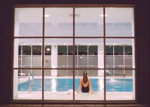 Eine Frau, die durch ein Fenster im Pool sitzt. in der Unterkunft Regency Park Hotel, Health Club & Spa in Newbury