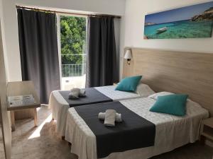 Habitación de hotel con 2 camas y ventana en Hotel Antares, en Cala d´Or