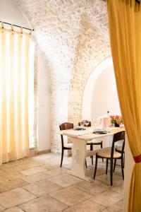 una sala da pranzo con tavolo, sedie e parete in pietra di La Casa di Vale a Martina Franca
