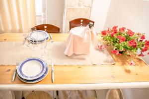 a wooden table with plates and glasses and flowers on it at La Casa di Vale in Martina Franca