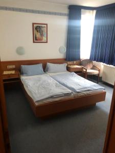 a bedroom with a large bed and a chair at Hotel Mylos in Sittensen