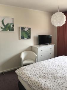 a bedroom with a bed and a tv and a chair at Apartement "Sam" in Wilhelmshaven