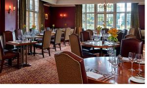 a restaurant with tables and chairs in a room at Macdonald Elmers Court Resort in Lymington