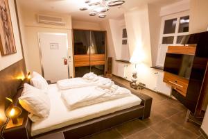 a bedroom with a bed with white sheets and a television at Aragon - Hotel - Garni in Tangermünde