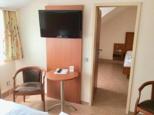 a room with a table and a television on a wall at Hotel Hubertus Hamacher in Willich