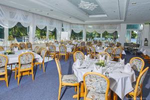 une salle à manger avec des tables et des chaises blanches dans l'établissement Seeblick, à Mühbrook