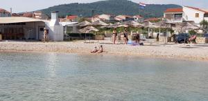 a group of people sitting on a beach near the water at Apartman Tribunj Luji i Andreja in Tribunj