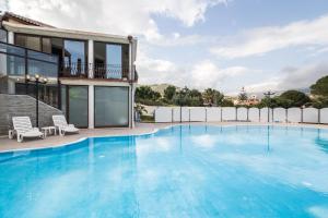 una grande piscina con acqua blu di fronte a una casa di Hotel Solanas a Solanas