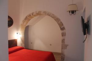 a bedroom with a red bed and an arch at Casa Giacchino in Noto