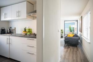 a kitchen with white cabinets and a chair in a room at Houseboat Lady Jane in Amsterdam