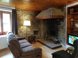 sala de estar con sofá y chimenea de piedra en Apartaments Can Bundanci, en Setcases