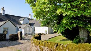 un village avec un mur en pierre et un arbre dans l'établissement Greenden Farmhouse, à Brechin