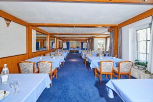 a row of tables in a restaurant with white tables and chairs at Seeblick in Mühbrook