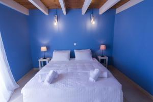 ein blaues Schlafzimmer mit einem großen Bett mit weißer Bettwäsche und Kissen in der Unterkunft Kefalonia Ammos Villa in Lixouri
