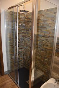a shower in a bathroom with a stone wall at La Torre Rooms in San Quirico dʼOrcia