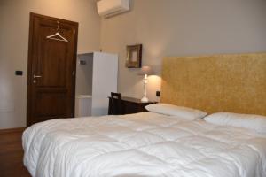 a bedroom with a white bed and a refrigerator at La Torre Rooms in San Quirico dʼOrcia