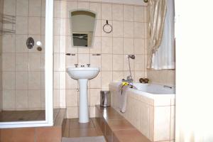 a bathroom with a sink and a toilet and a tub at Cycas Guest House in Malelane