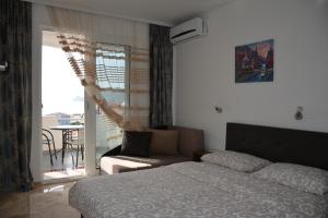 a bedroom with a bed and a couch and a balcony at Studios Seaview in Dobra Voda