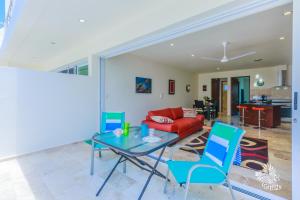 a living room with a red couch and blue chairs at Estrella del Mar - Condo 101 in Isla Mujeres