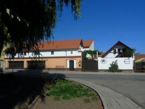 a white building with a brown roof and a street at Pension Černý jezdec in Lednice