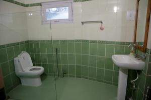 a green tiled bathroom with a toilet and a sink at Hutton Cottage By Stay Native in Nainital +23 photos