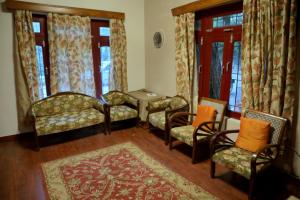 a living room with chairs and windows and a rug at Hutton Cottage By Stay Native in Nainital