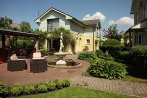 a garden with a fountain in front of a house at Vila Florena Garden in Palanga