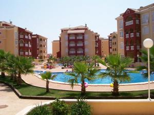 a large pool with palm trees in front of buildings at Cosy Cwtch 2 in Los Alcázares