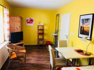 a living room with yellow walls and a table and chairs at Gästehaus Kerle in Dossenheim