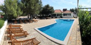 einen Pool mit Holzstühlen und eine Gruppe in der Unterkunft Rooms Camp Marina in Lozovac