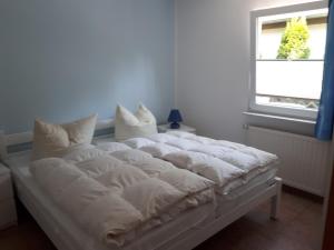 Cama blanca en habitación con ventana en Feriensiedlung Rother en Trassenheide