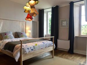 a bedroom with a bed and a chandelier at L'Ermitage in Saint-Vaast-la-Hougue