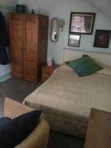 - une chambre avec un lit et une armoire en bois dans l'établissement Cornerstones Guest House, à Sale