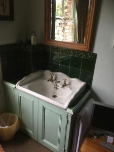 een badkamer met een witte wastafel en een spiegel bij Cornerstones Guest House in Sale