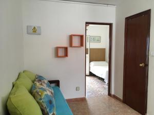 a living room with a green couch and a bedroom at Apartamentos Calypso in Punta Umbría