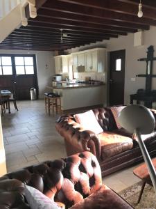 a living room with a leather couch and a kitchen at Ahakista Lodge in Ahakista