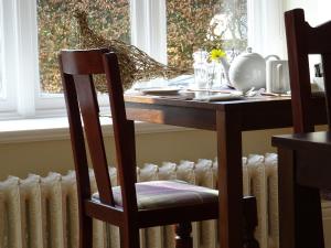 a dining room table with a chair and a window at Grendon Bed & Breakfast in Buxton