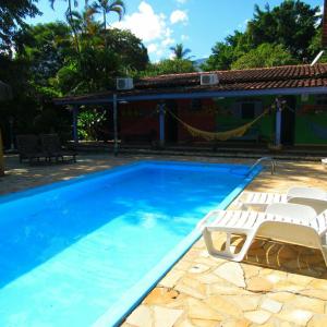 a swimming pool with two lounge chairs and a house at Pousada do Sidão in Ilhabela