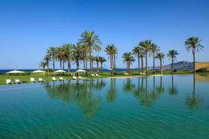 une grande étendue d'eau avec des palmiers et des chaises blanches dans l'établissement Verdura Resort, à Ribera