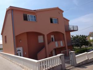 a orange house with a white fence in front of it at Apartman Lucija in Zadar