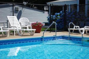 a swimming pool with white chairs at Mariner Motel in Falmouth