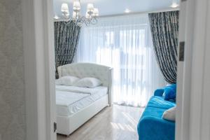 a bedroom with a white bed and a blue couch at Apartment Status in Kaliningrad